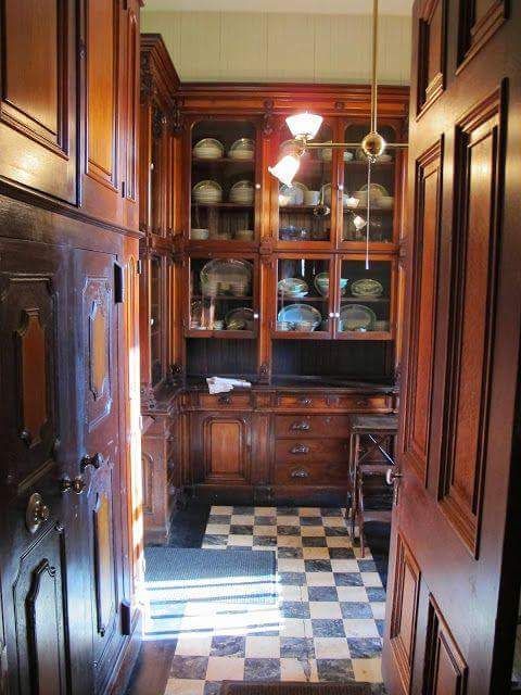 an old fashioned kitchen with wooden cabinets and checkered flooring