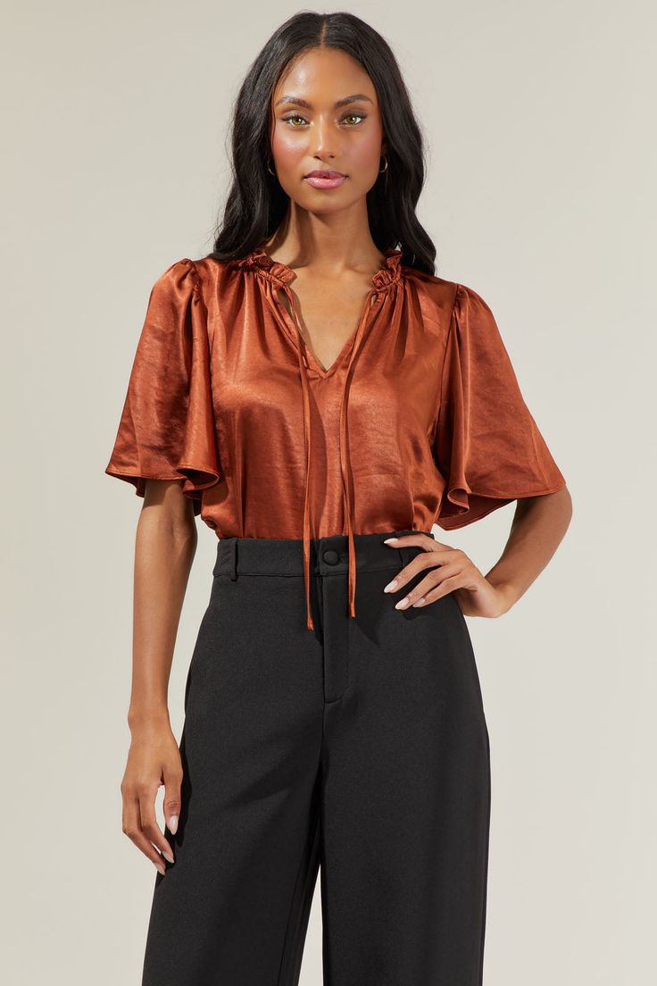 Step into any room and leave a lasting impression in the Angela Satin Tie Neck Flutter Sleeve Blouse! Its cute look with a ruffle trim, split neck can be secured by a tie string detail. Flowy short sleeves offers a more modest look, along with a relaxed bodice. Wear it tucked or as is into your favorite high waisted bottoms and pair it with mules.- Flouncy sleeves- Split neckline- Ruffle trim- Relaxed fit- Comes in 4 colorsSize + Fit - Model is 5'8" and wearing size XS- Measurements taken from s Chic Brown Short Sleeve Blouse, Brown Ruffled Short Sleeve Blouse, Elegant Brown Short Sleeve Blouse, Flouncy Sleeves, Flutter Sleeve Blouse, High Waisted Bottoms, Flowy Shorts, Tie Neck, Sweater Weather