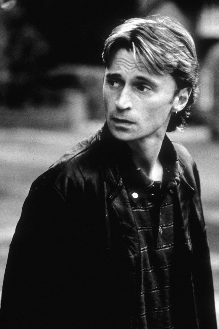 black and white photo of man in leather jacket looking off to the side with serious look on his face