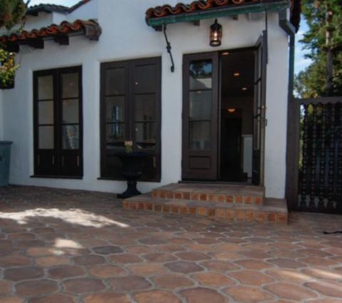 a white house with black doors and brick steps leading up to it's entrance