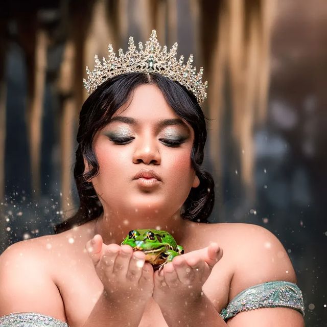 a woman wearing a tiara and holding a frog in front of her face with water droplets around her