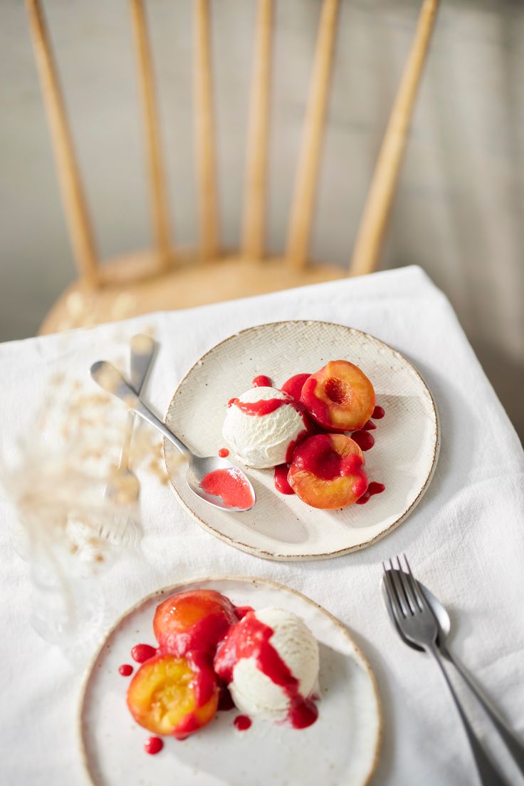 two plates with desserts on them sitting on a table next to forks and spoons