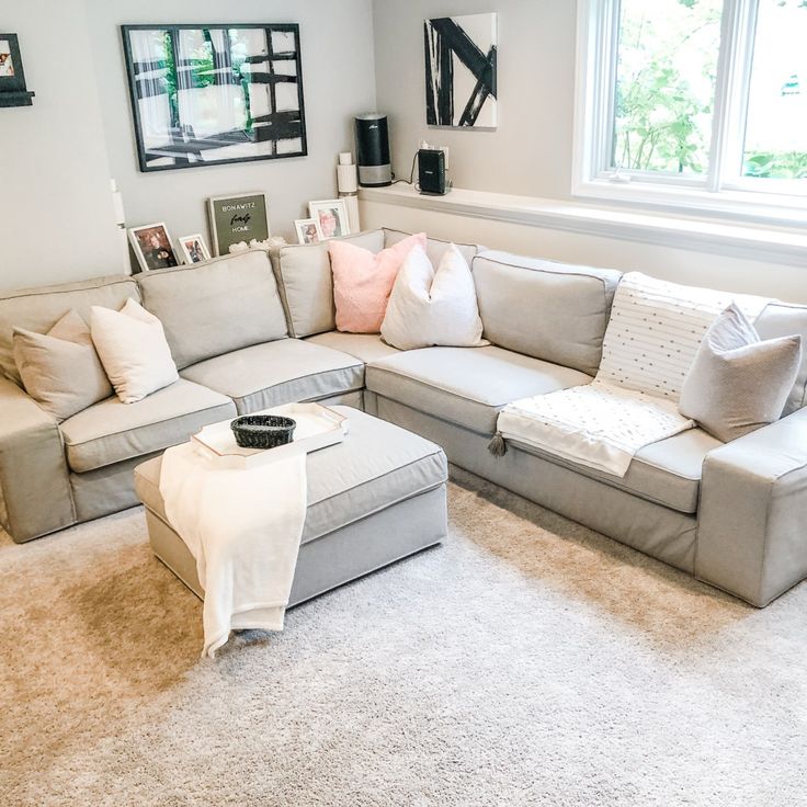 a living room filled with lots of furniture next to a large window on top of a carpeted floor