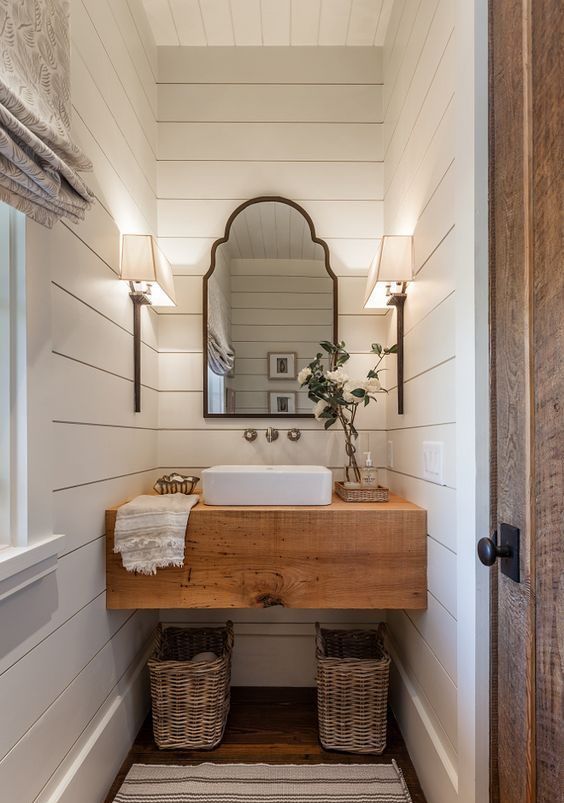 a bathroom with a sink, mirror and two wicker baskets on the floor in front of it