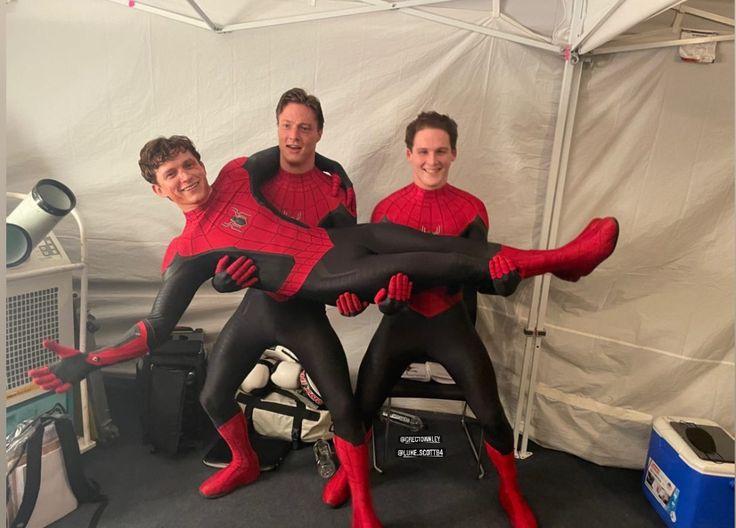 three men in spider - man suits posing for a photo together with their legs stretched out