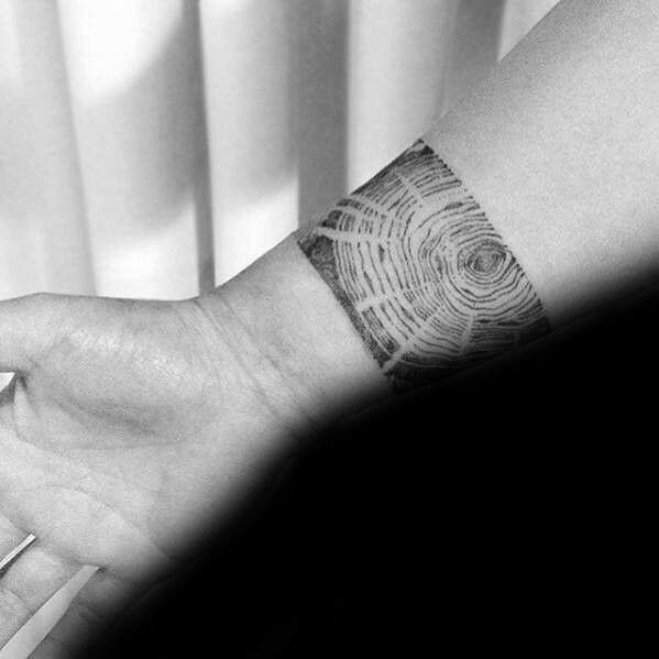 a person's arm with a wrist tattoo that has a tree ring on it