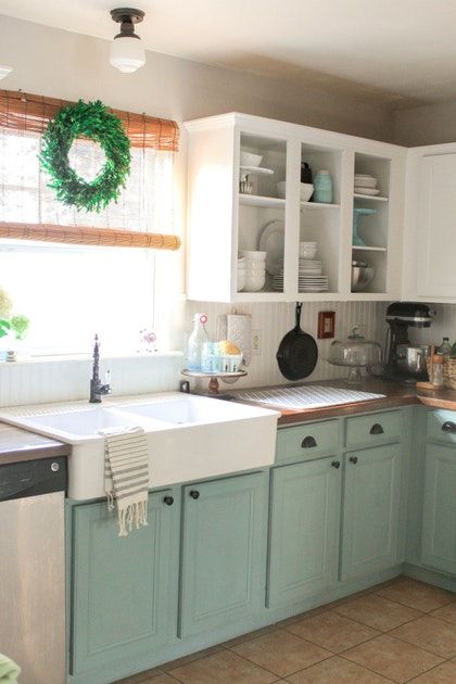 a kitchen filled with lots of white cabinets and green cupboards next to a window