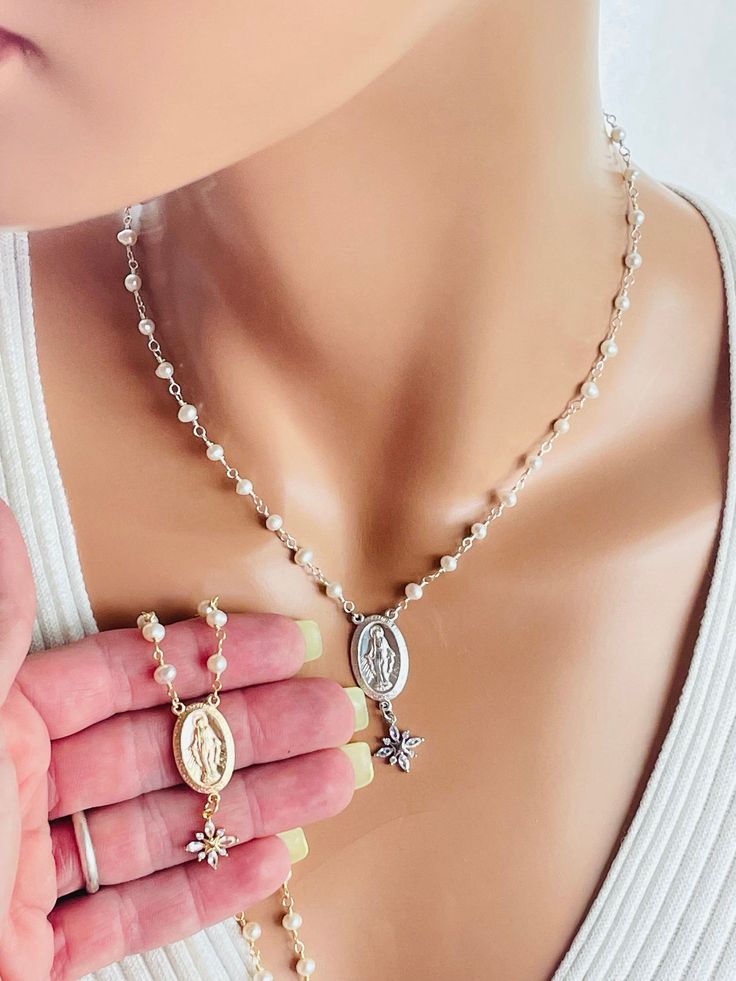 "This is a beautiful Mary miraculous medal pearl necklace made in 925 sterling silver or  14K gold filled. This beautiful necklace features Mary miraculous medal that measures 23 x 14 mm hanging from freshwater pearls that measure 3.5 to 4.5 mm. There is a beautiful CZ flower that hangs from the pendant, measures 12 mm. Spring clasp and back. Model has a small neck, is wearing a 15 inch length. Please note the length is the measurement around the neck. It does not include the drop. Miraculous drop with star measures 2.25\". This necklace comes in many lengths. Choose your desired length and metal. I do recommend that you measure around your neck where you want the medallion  to land. Comes in a gift box ready to present. Please pay attention to delivery time stated on this listing. I do of Catholic Jewelry Necklace, Pearl Gifts, Catholic Jewelry, Charm Necklaces, Miraculous Medal, Beautiful Necklace, Virgin Mary, Gift For Mom, Pay Attention