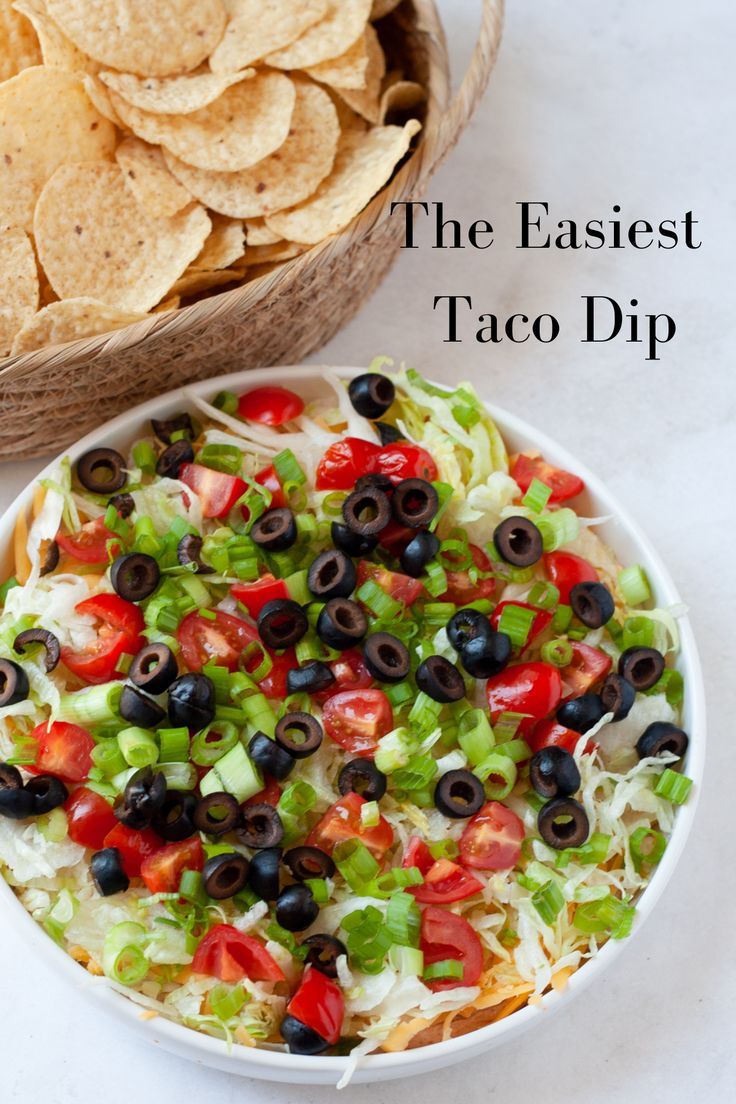 an easy taco dip with tortilla chips and black olives in a bowl