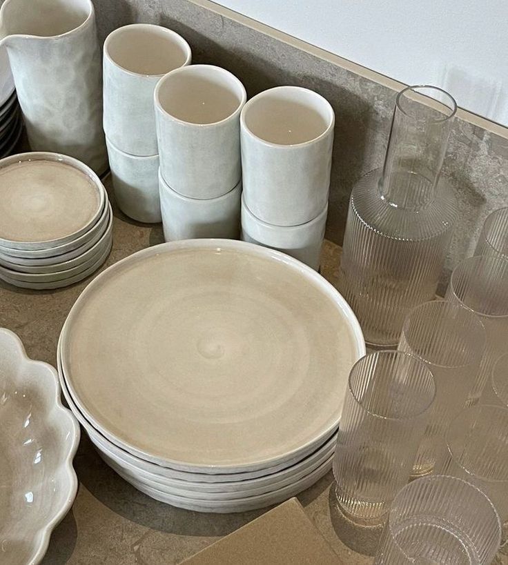 a table topped with lots of white dishes and cups next to each other on top of a counter