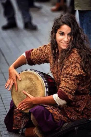 a woman sitting on the ground holding a drum