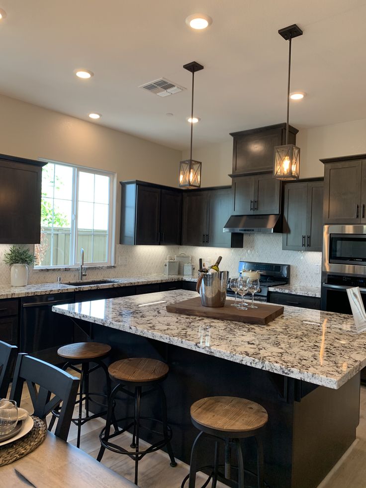 a kitchen with black cabinets and marble counter tops