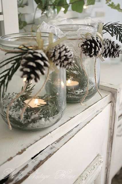 two mason jars filled with pine cones and candles