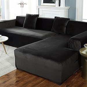 a living room with a large black couch and coffee table in front of a fireplace