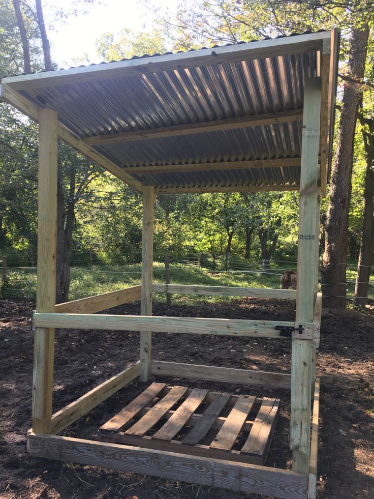 a wooden platform with a metal roof in the woods