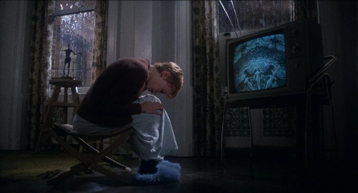 a woman sitting on a chair in front of a tv with her face close to the ground