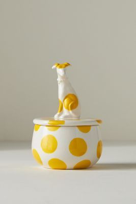 a yellow and white dog figurine sitting on top of a polka dot covered bowl