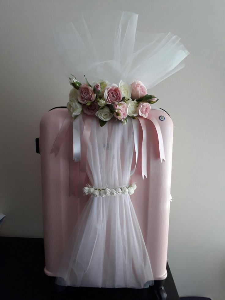 a pink suitcase decorated with flowers and tulle