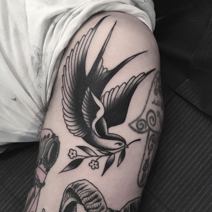 a black and white tattoo on the arm of a person's left arm, with an image of a bird in flight