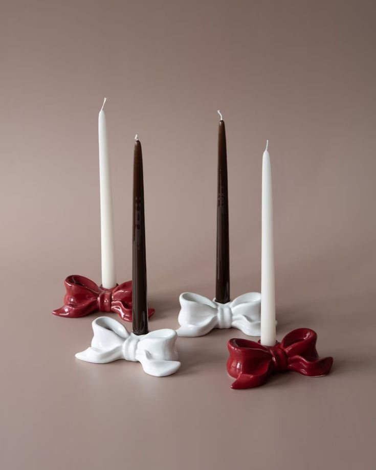 three candles with bows on them sitting next to each other in front of a brown background