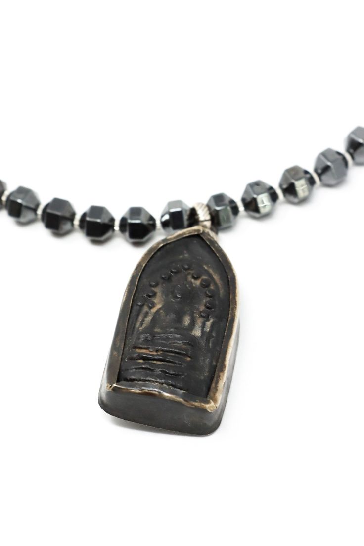 The Mya Lambrecht Buddha Necklace is minimal yet striking! Material: Natural stones, metalOrigin: Made in Minnesota Hook closure Handmade sitting Buddha from Thailand Ancient Chinese I-Ching coin Hematite 28" long Mya Lambrecht incorporates everyday objects into her pieces that are seemingly out of place. Her pieces create a relationship between people and the earth. Spiritual Coin-shaped Jewelry With Large Pendant, Spiritual Brass Jewelry With Oxidized Finish, Spiritual One-of-a-kind Metal Necklace, Oxidized Pendant For Meditation, Silver Brass Amulet Coin Necklace, Artisan Medallion Necklace For Meditation, Handmade Brass Spiritual Coin Necklace, Oxidized Finish Pendant For Meditation, Oxidized Amulet Pendant Necklace