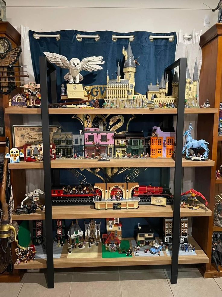 a display case filled with lots of different types of toy trains and buildings on top of wooden shelves