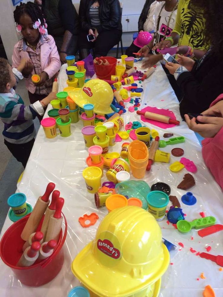 children are sitting at a table covered in toys