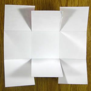 several pieces of paper are folded up on a wooden surface with one piece cut out