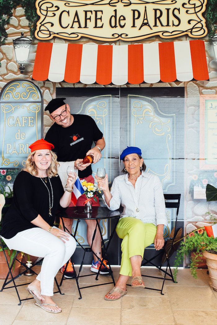 three people are sitting at a table in front of a cafe