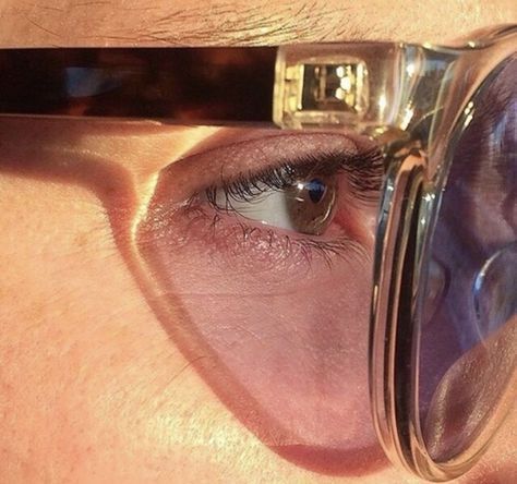 a close up of a person wearing glasses with their reflection in the lens and looking into the distance