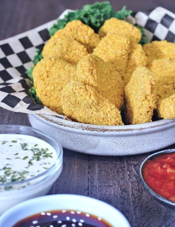 some fried food is in a bowl on a table with sauces and ketchup