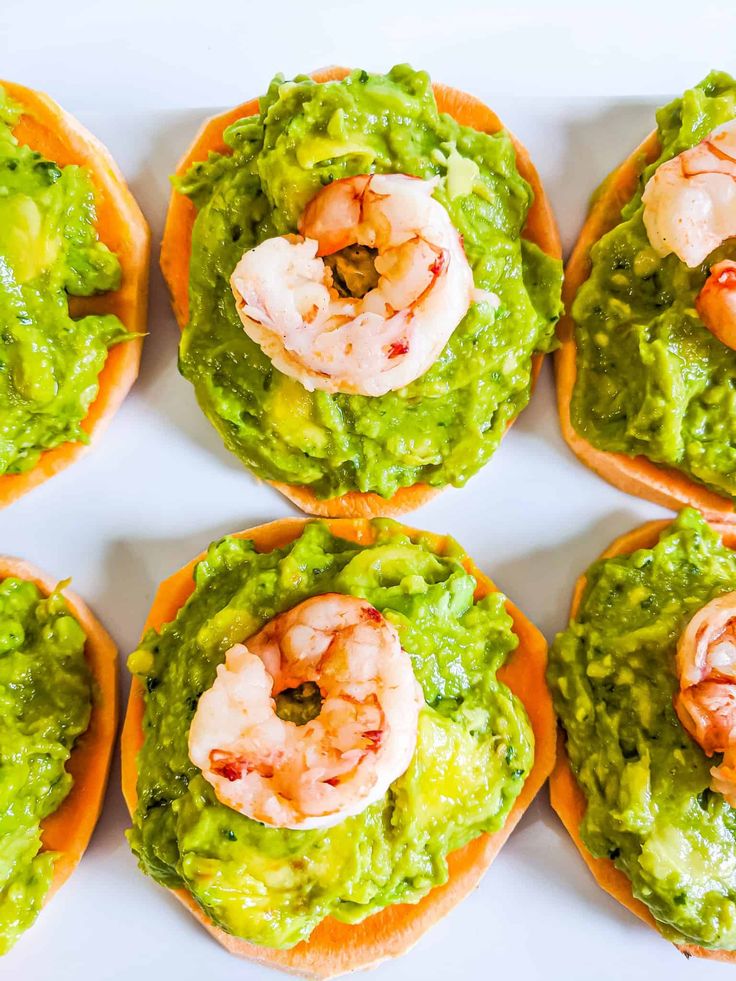 several small sandwiches with shrimp and guacamole on them are arranged in rows