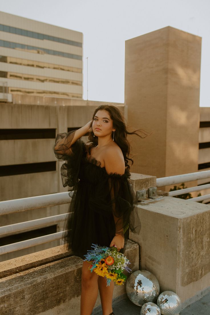 a woman in a black dress leaning against a wall