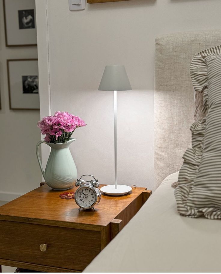 a bedroom with a bed, lamp and flowers on the night stand in front of it