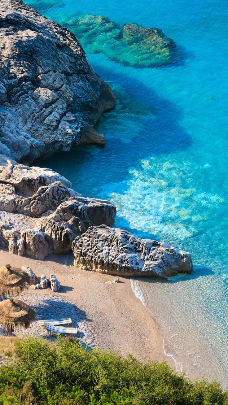 an aerial view of a sandy beach with umbrellas on the sand and blue water