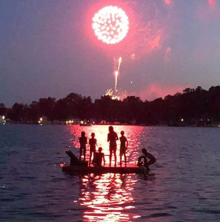 people on a boat watching fireworks in the sky