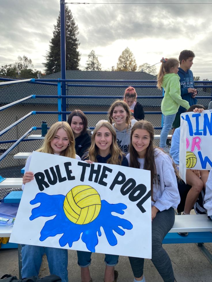 a group of young women holding up signs in front of a bleachers bench