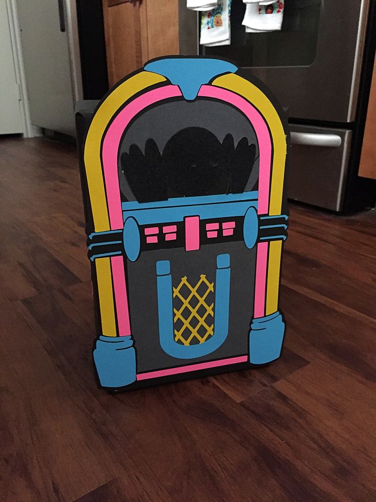 a cardboard cutout of a jukebox on the floor in front of an oven