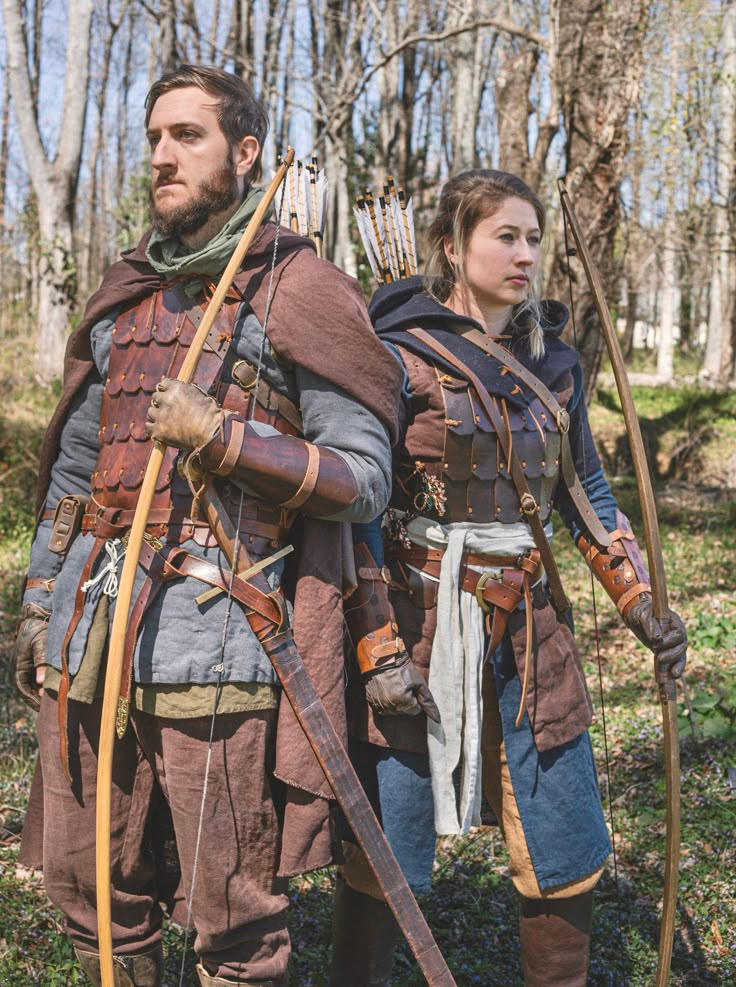 a man and woman dressed up in medieval clothing with bows and arrows standing next to each other