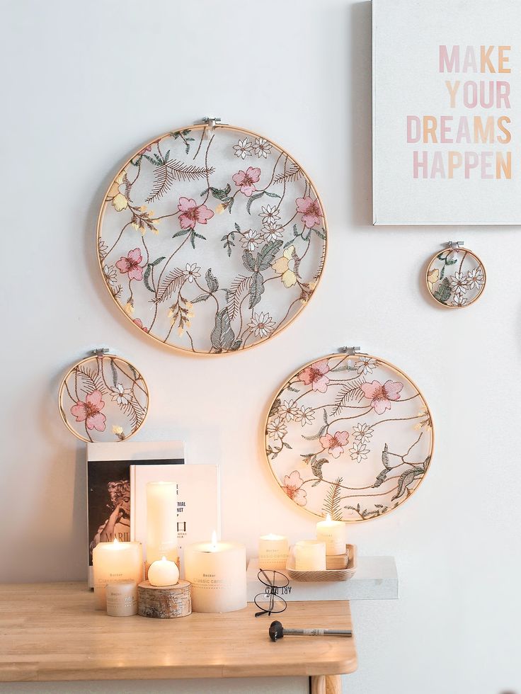 three plates with flowers on them are hanging on the wall next to candles and pictures