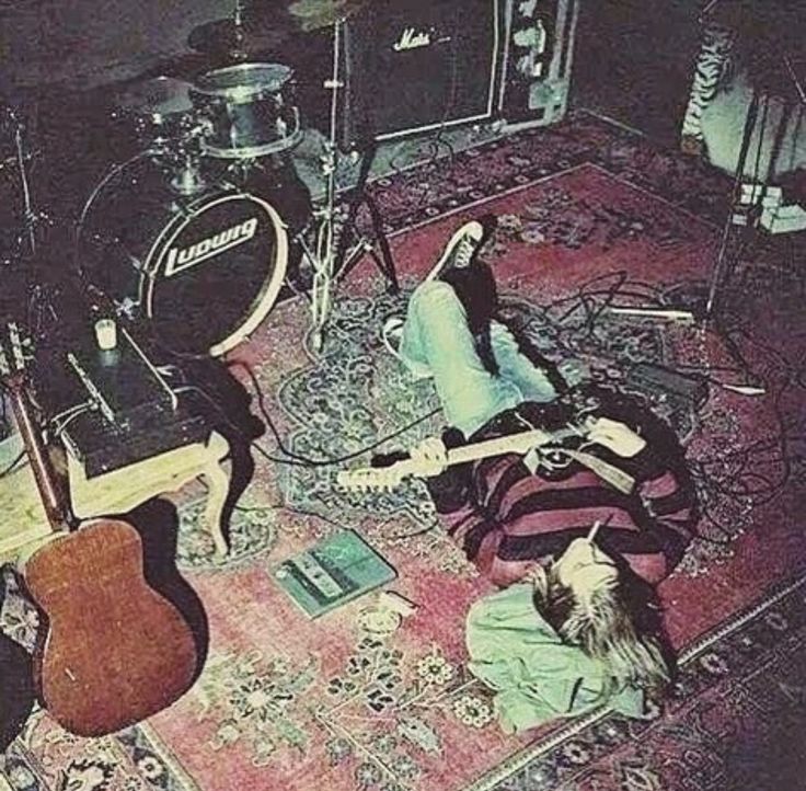 a group of people laying on top of a rug next to guitars and amps