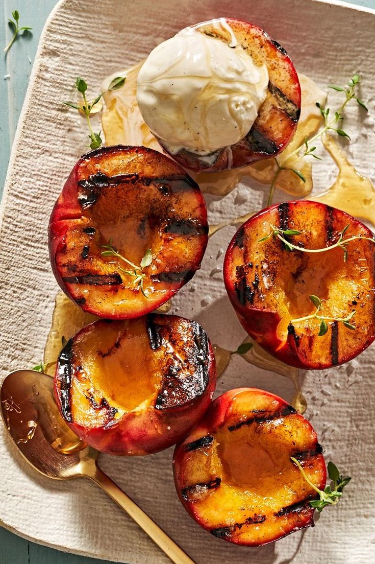 grilled peaches on a plate with a wooden spoon