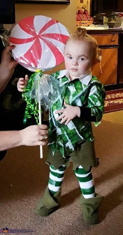 a young child dressed in green and white holding an umbrella with candy canes on it