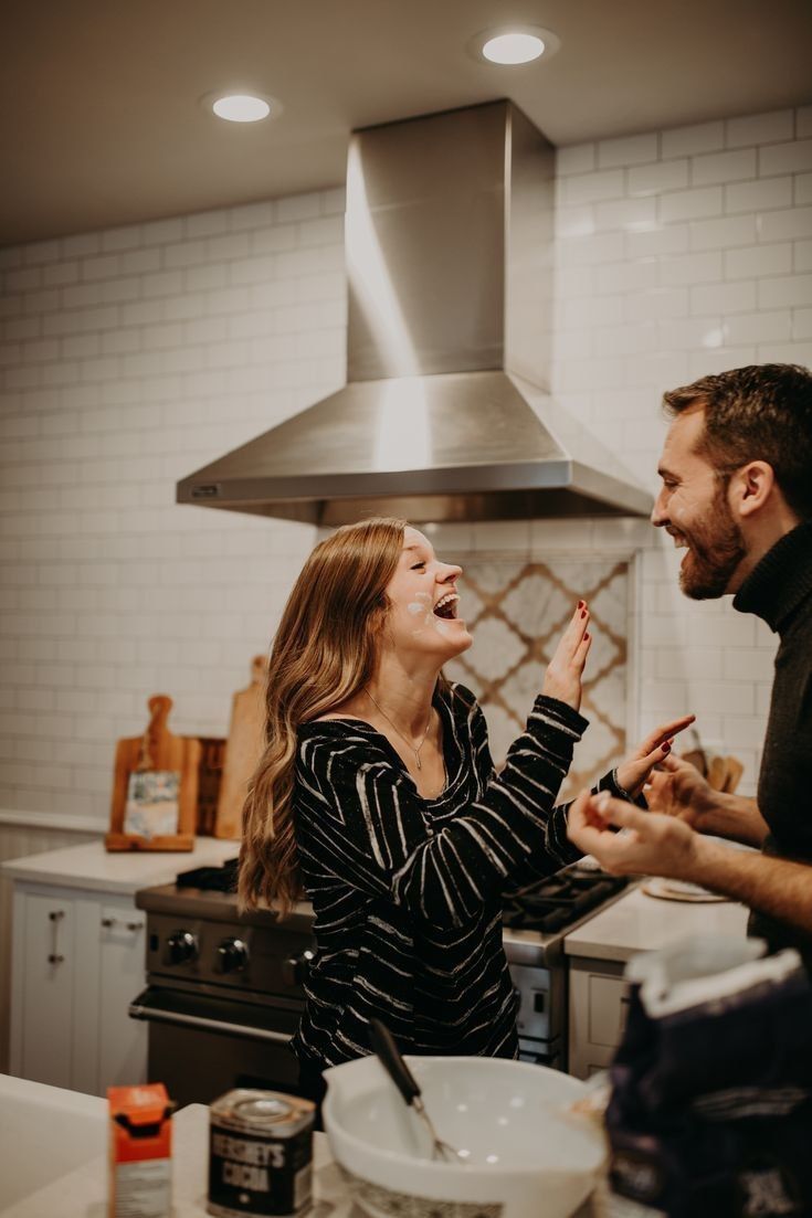 a man and woman are laughing in the kitchen