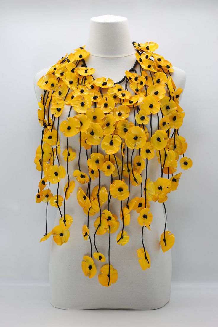 a white mannequin with yellow flowers on it's neck and black beads