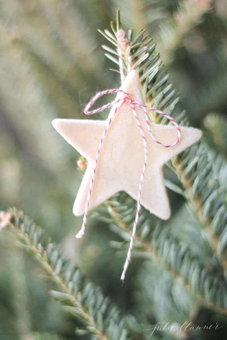 a pink star ornament hanging from a christmas tree