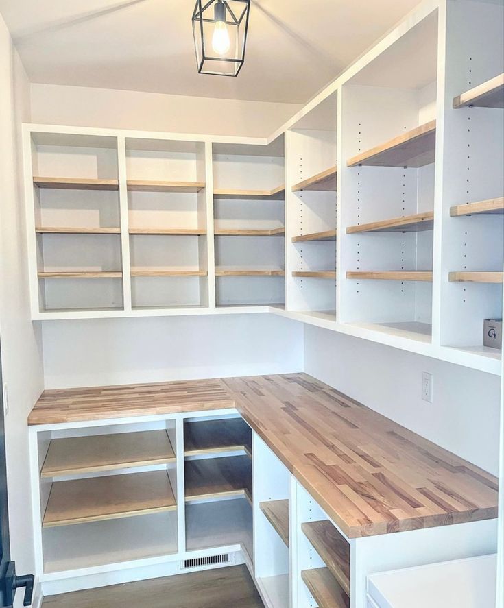 an empty walk - in closet with shelves, drawers and lights above the countertop