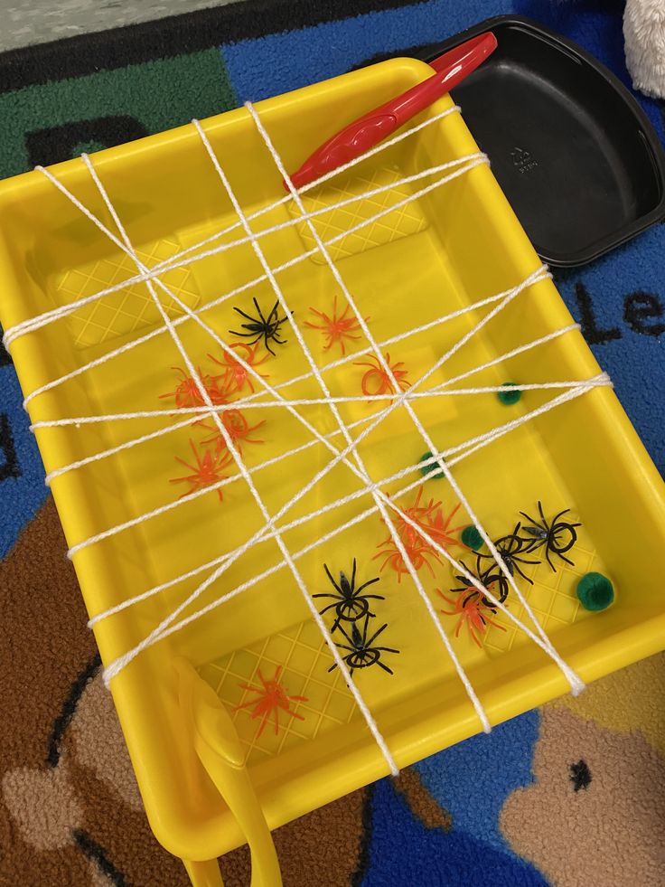 a yellow tray with spider magnets on it and a red pen in the middle