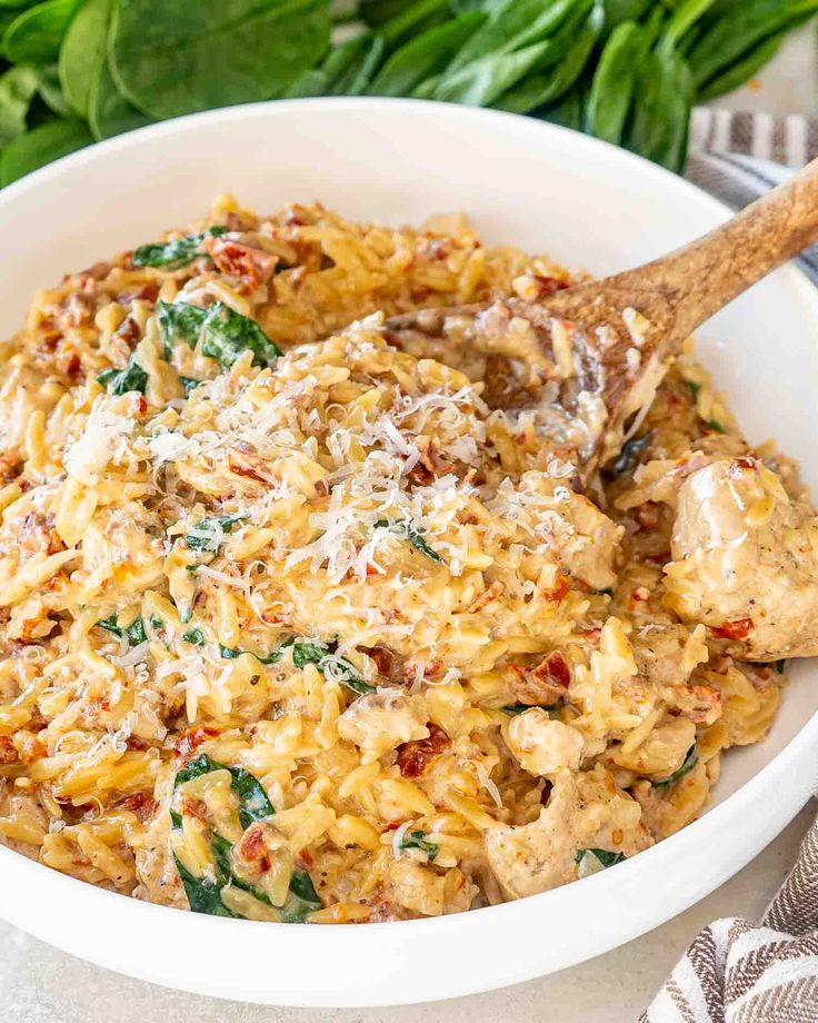 a white bowl filled with pasta and spinach