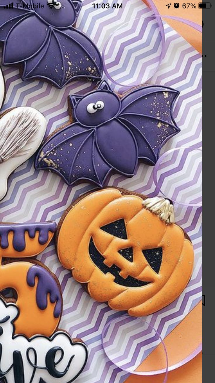 some decorated cookies sitting on top of a purple and white plate with an orange bat